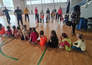 Dzieci na hali sportowej zotają podzielone na drużyny przez instruktorów sportowych.