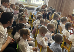 Dzieci i nauczyciele na widowni oglądający występ.