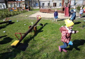 Dzieci w ogrodzie przedszkolnym zbierają śmieci.