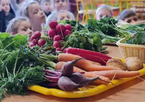 Nauczycielka prezentuje warzywa dzieciom.