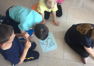 Dzieci siedzą na podłodze. Układają puzzle.