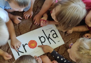 Dzieci w małej grupce wskazują kropkę w wyrazie kropka.