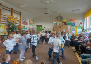 Dzieci ubrane odświętnie tańczą taniec Trojak na środku sali. Goście klaszczą.