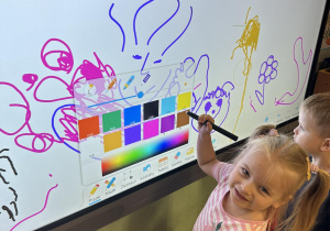 Dziewczynka rysuje na monitorze interaktywnym.