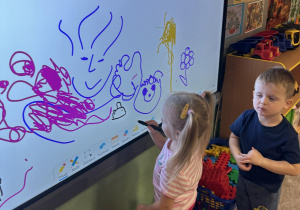 Dzieci rysują na monitorze interaktywnym.