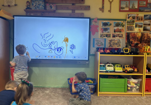 Dzieci rysują na monitorze interaktywnym.