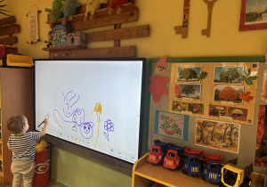 Dziecko rysuje na monitorze interaktywnym.