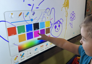 Dziecko rysuje na monitorze interaktywnym.