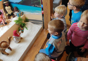 Dzieci podziwiają wystawę lalek.