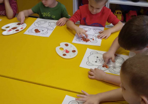 Dzieci malują farbami misia.