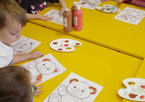 Dzieci malują farbami misia.