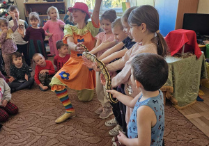 Dzieci na scenie trzymają węża.