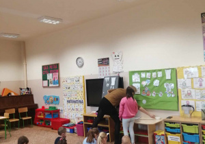 Nauczyciel pomaga dziecku podczas zadania przy tablicy.