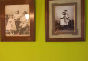 Na zdjęciu są dwie starodawne fotografie. Wiszą na ścianie. Jedna obok drugiej w brązowych ramkach.