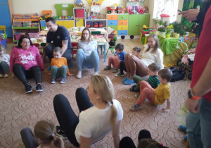 Dzieci z nauczycielem i rodzicami wspólnie biorą udział w zabawach.