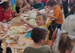 Dzieci wspólnie z rodzicami robią zdrowe kanapki.